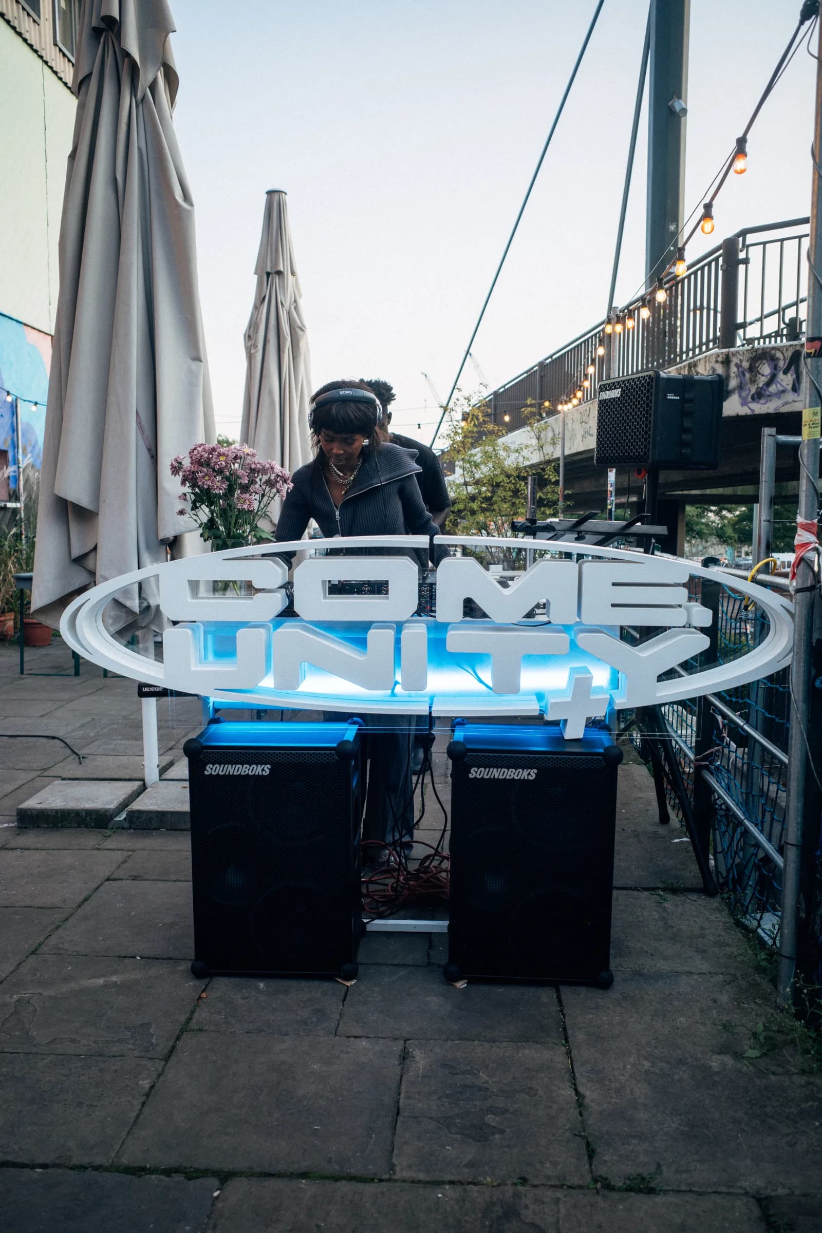A come.unity DJ set under the illuminated come.unity sign